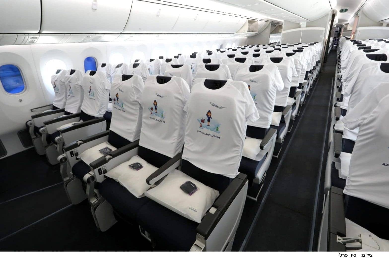 Rows of seats aboard EL AL’s Boeing 787, each one dressed in a white printed T-shirt